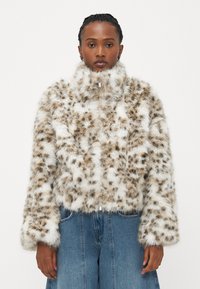 Faux fur-jakke med høy krage, med et flekkete mønster i brunt og hvitt. Den har lange ermer og en frontlynlås.