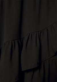Tissu noir avec des volants en couches montrant la texture et les plis doux du matériau.