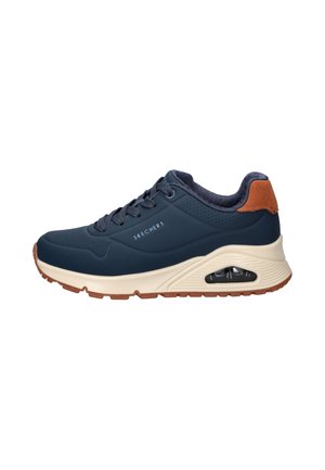 Baskets Skechers bleu marine avec semelle beige, coussin d'air visible, accent marron au talon et lacets sur fond blanc.
