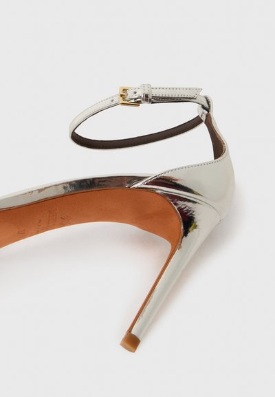 Ασημένιο πατεντέ δέρμα ψηλοτάκουνο παπούτσι με μυτερή μύτη, λουρί αστράγαλου και τακούνι στιλέτο 10 εκ. Πορτοκαλί εσωτερική επένδυση και σκούρα σόλα.