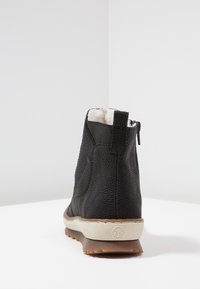 Svarta ankelboots i texturerat läder, med elastiska sidopaneler och dragkedja. Ljusbrun sula med en kontrasterande logodetalj.