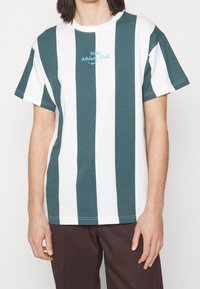 Zelené a bílé pruhované tričko s krátkým rukávem, kulatým výstřihem a logem "Nike Athletic Club" v modré barvě, vyrobené z bavlny.