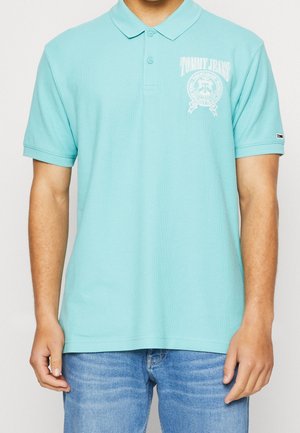 Turkusowa koszulka polo z teksturowanej tkaniny, z kołnierzykiem i logo na lewej stronie klatki piersiowej. Krótkie rękawy i proste wykończenie.