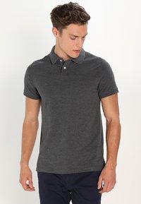 Polo-shirt gris foncé en coton, avec un col classique, des manches courtes et une patte de boutonnage à trois boutons. Texture douce et coupe décontractée.