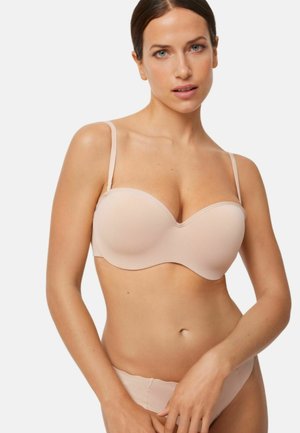 Sujetador beige acolchado sin costuras con aros, tirantes ajustables y textura suave. Diseño minimalista sin patrones visibles ni detalles metálicos.