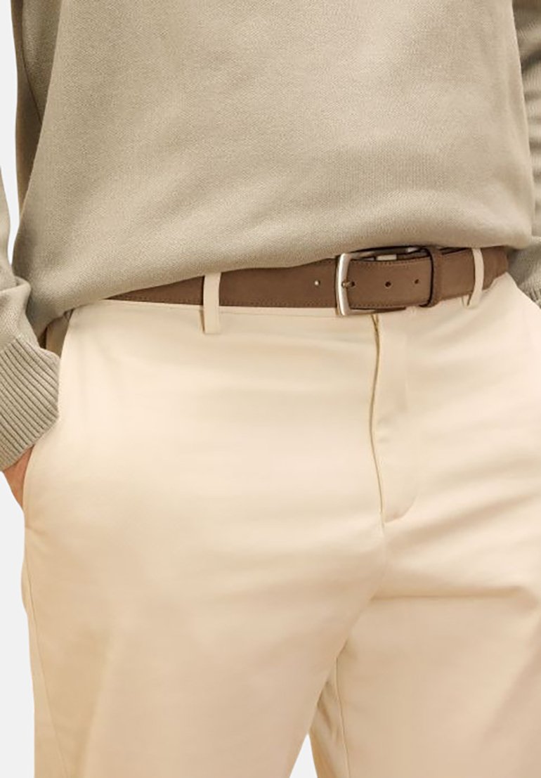 Beige trousers with slim fit, featuring a flat front, side pockets, and a brown leather belt with a silver buckle. The fabric has a smooth texture.