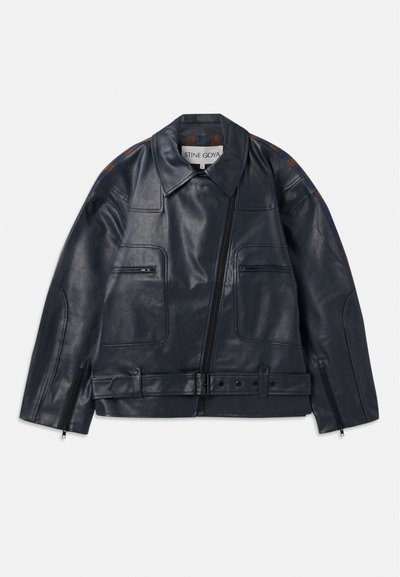 Veste en cuir bleu marine au design structuré, avec une fermeture éclair à l'avant, deux poches poitrine et des accents marron contrastants sur les épaules.