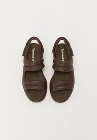 Ruske nahkatossut, joissa on kaksi leveää remmiä, avonaiset varpaat ja tuki takana kantapäässä. Pehmustettu pohja, jossa Timberlandin logo näkyvissä.