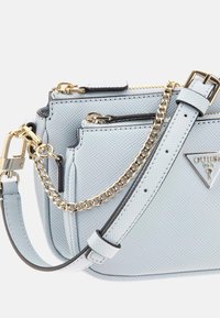 Lyseblå, tekstureret crossbody taske med guld hardware, kædeaccent og lynlåslommer. Har et trekantet logo og justerbar skulderrem.