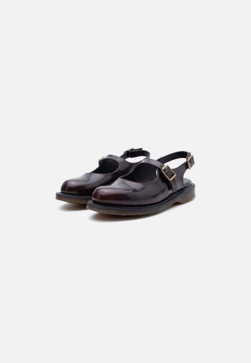 Scarpe stile Mary Jane in pelle marrone scuro con fibbie laterali e suole spesse in gomma, mostrate frontalmente su sfondo bianco.