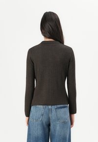 Brun ribbad tröja med en figurnära design och långa ärmar, parat med ljusblå vida jeans. Enkel, minimalistisk stil.