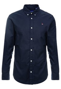 Námořnická modrá košile na dlouhý rukáv s knoflíky vyrobená z bavlněné látky. Má klasický límec, bílé knoflíky a jemné logo hory na hrudi.