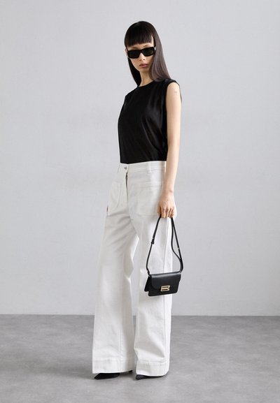 Schwarzes ärmelloses Oberteil, weiße weite Hose, schwarze Handtasche mit goldenen Beschlägen, spitze schwarze Absätze, glatte Stoffstruktur, minimalistisches Design.