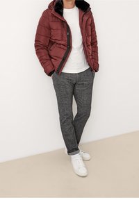 Bordowy kurtka puchowa z czarnym futrzanym kapturem, biała koszulka, szare spodenki w wzory i białe trampki z podwiniętymi mankietami.