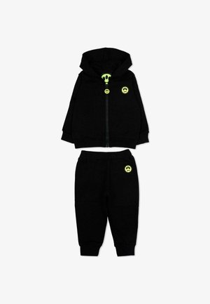Tuta da bambino nero con giacca con cappuccio e zip e pantaloni, con icone di faccine sorridenti verde neon sulla giacca e sui pantaloni.