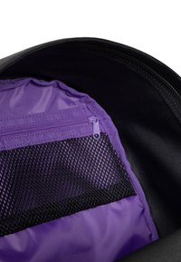 Interior de mochila negra con un bolsillo con cremallera morado y una sección de malla negra. Textura suave con un diseño organizado para almacenamiento.