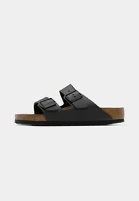 Sandalo nero a due cinturini in materiale liscio, con fibbie regolabili e una soletta in sughero naturale con suola in gomma testurizzata.