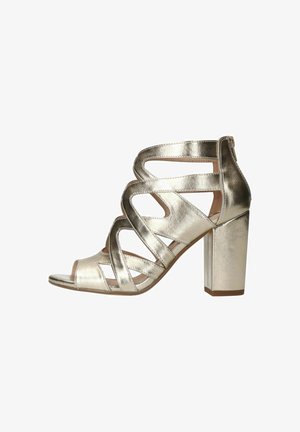 Metalen gouden sandalen met hakken, voorzien van een uitsnijdingsontwerp, open teen en een blokhak. Soepele textuur met meerdere banden voor ondersteuning.