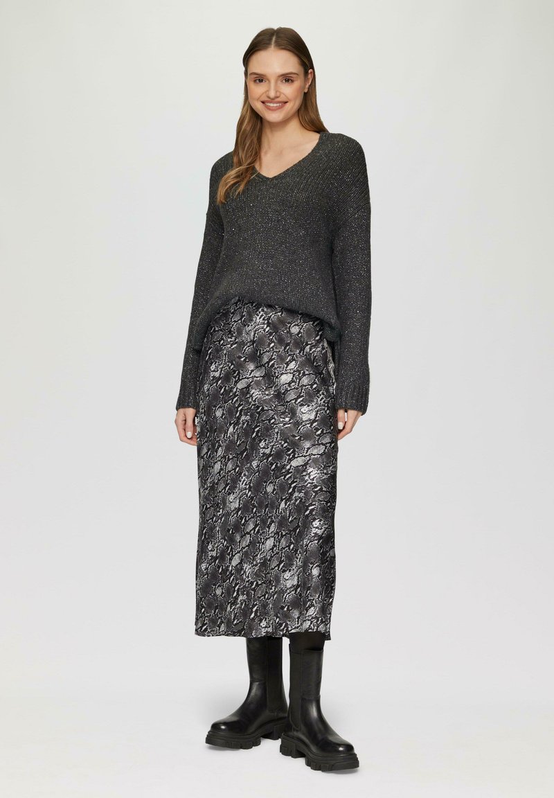 Donkergrijze gebreide sweater met een V-hals en lange mouwen, gecombineerd met een zwarte midi-jurk met slangpatroon en chunky zwarte enkellaarsjes.