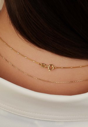 Goldene geschichtete Halsketten mit verschiedenen Kettenstilen. Die oberste Kette verfügt über einen Karabinerverschluss; jede Kette hat unterschiedliche Texturen und Oberflächen.