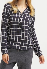 Navy blouse met een wit ruitpatroon, lange mouwen, knoopsluiting en een relaxte fit. Gemaakt van een soepele, lichte stof.