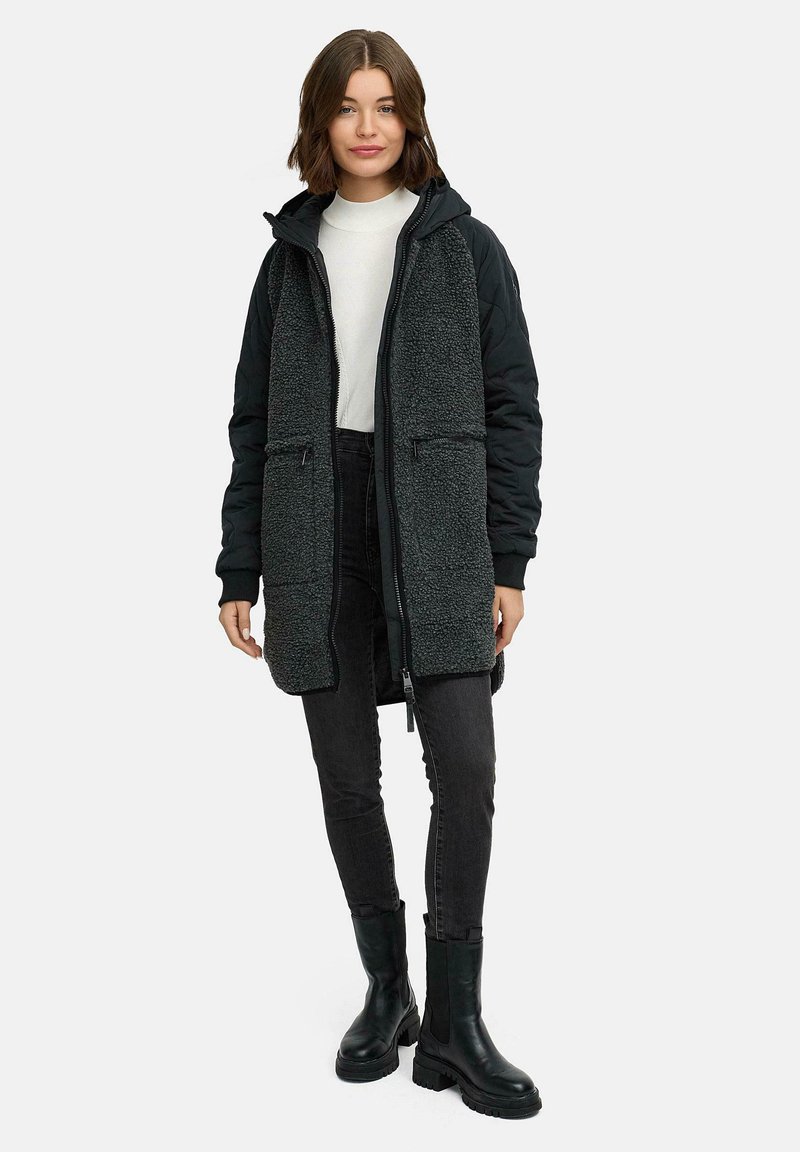 Lång huva jacka med en texturerad mörkgrå fleeceframsida och svarta quiltade ärmar, som har två zip-fickor och en framslupp med dragkedja.