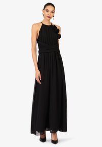 Schwarzes Maxikleid mit Halterneck und plissiertem Stoff, mit einer floralem Akzent an der Schulter und einem taillierten Bund. Glatte Textur und fließendes Design.