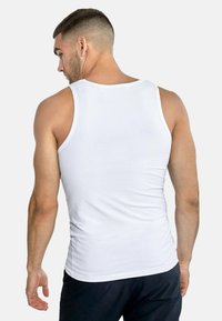 Weißes Tanktop aus Baumwolle mit Rundhalsausschnitt und ärmellosem Design. Glatte Oberfläche mit tailliertem Schnitt, von hinten gezeigt.