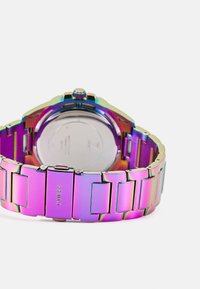 Montre métallique avec un bracelet en acier inoxydable aux couleurs arc-en-ciel, présentant des maillons polis et un boîtier circulaire avec une couronne texturée et un dos lisse.