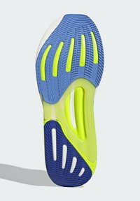 Shoe sole featuring a blue base, yellow accents, and white grooves for traction. Textured rubber material with visible patterns.