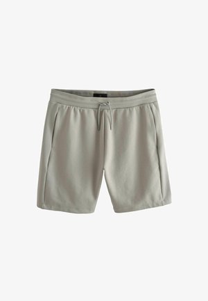 Heledad hallid spordihüpped, mis on valmistatud pehmest kangast, millel on elastne vöökoht, stringsulgemine ja küljetaskud.