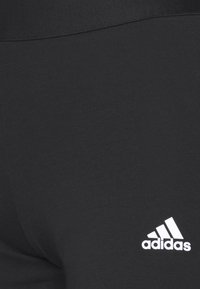 Black fabric with white Adidas logo positioned near the lower right corner.