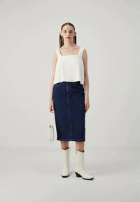 Top court blanc, jupe crayon en denim bleu, bottines blanches. Design minimaliste, silhouette ajustée, texture lisse et accents simples.