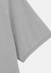 T-shirt gris à manches courtes en tissu doux et texturé. L'ourlet est soigneusement fini et la manche a une coupe décontractée.