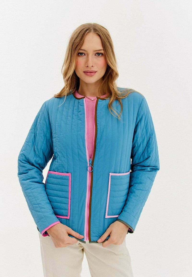 Dżinsowa niebieska kurtka pikowana z różowym zamkiem i wykończeniem, z dwiema przednimi kieszeniami obramowanymi różowym kolorem. Gładka tekstura i luźny krój.