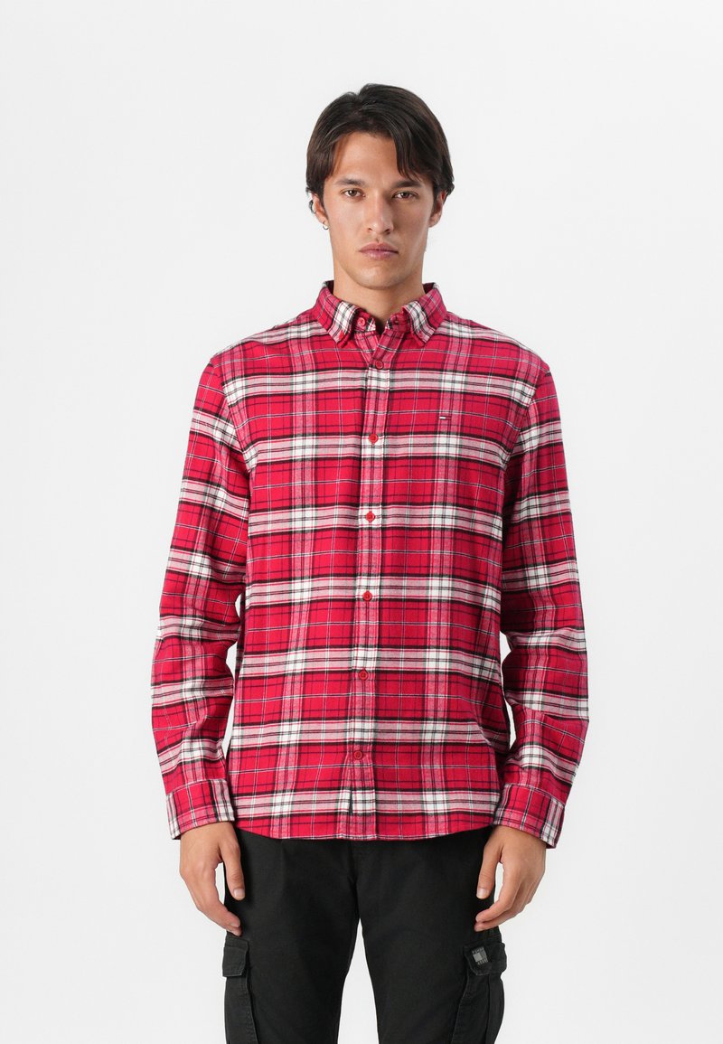 Camisa de cuadros roja y blanca con botones y mangas largas, hecha de una tela con textura suave. Presenta un cuello y cierre frontal con botones.