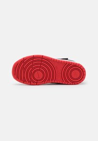 Rød gummisål med cirkulært mønster, der har et centralt Nike-logo. Overdel viser muligvis kontrasterende farver, materialerne er ikke synlige.