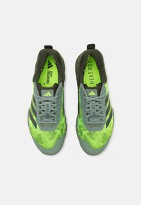 Scarpe sportive verdi e grigie con tomaia in rete testurizzata, strisce nere e suole ammortizzate. Presentano lacci e dettagli di marca all'interno.