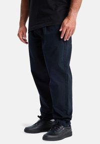Navy blauwe broek met een losse pasvorm, met een vlakke voorkant en zijzakken. Gecombineerd met zwarte sneakers. Gladde stofstructuur.