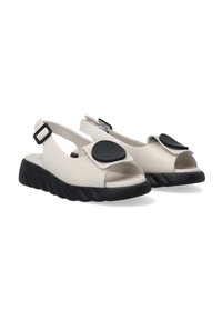 Beige leren sandalen met open tenen, slingback ontwerp, zwarte cirkelvormige versiering en een gestructureerde zwarte buitenzool.