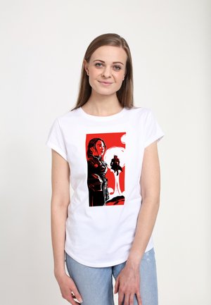 Biała koszulka z krótkim rękawem z graficznym wzorem w czerni i czerwieni, przedstawiającym kobietę oraz sylwetkę na kontrastowym tle.