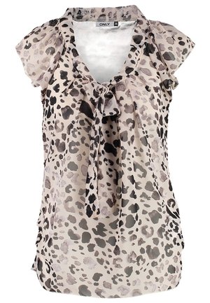 Vrouw loopt, draagt een blouse met luipaardprint, zwarte smalle broek, taupekleurige enkellaarzen en draagt een zwarte tote tas.