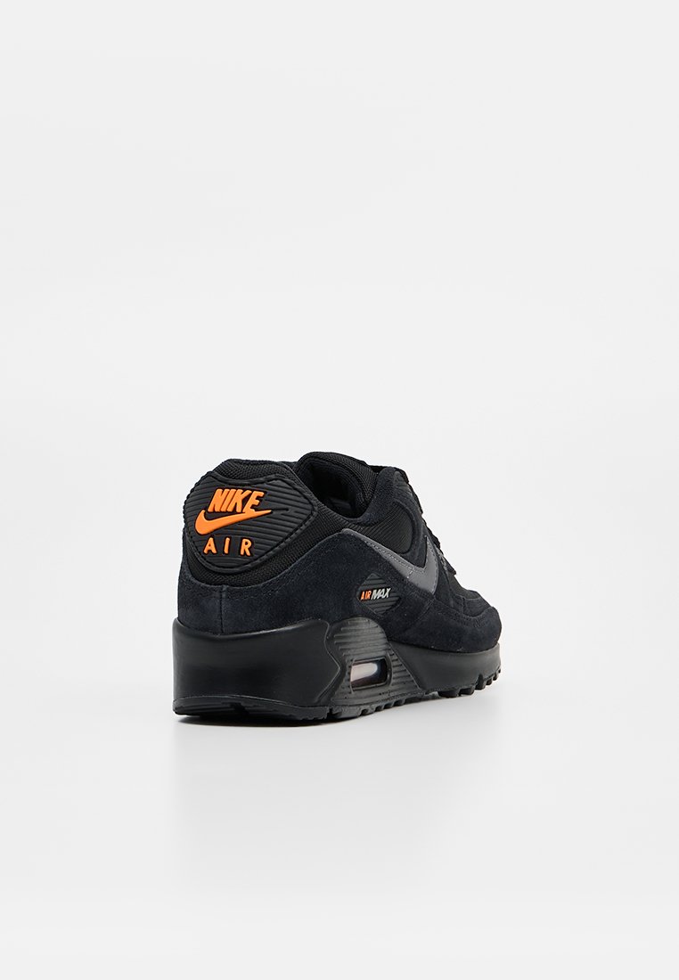 Baskets Nike Air Max noires avec logo orange sur le talon, semelle à coussin d'air visible et swoosh gris sur le côté, sur fond blanc uni.