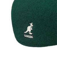 Sombrero verde de fieltro con un logo de canguro bordado y texto que dice "KANGOL". La textura es suave y la forma es redondeada.