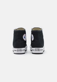 Høye svarte kanvas sneakers med hvite gummisåler, med kontrasterende hvite sømmer og klassiske logopatcher på sidene.