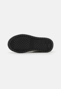 Semelle de chaussure en caoutchouc noir avec une surface texturée, présentant un motif en grille et le logo de la marque. Bout arrondi et talon plat.