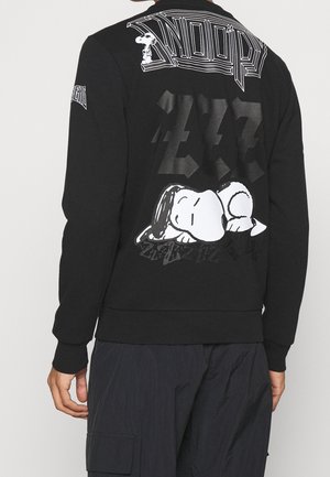 Czarna bluza z nadrukiem śpiącego Snoopy’ego, dużym napisem „ZZZ” i stylizowanym napisem „Snoopy” na plecach.