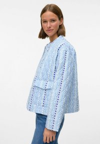 Blåmönstrad jacka med geometriska och vågiga motiv, rund halsringning, knappstängning och en framficka. Strukturerad passform.