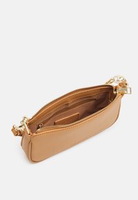 Vaaleanruskea nahkalaukku, jossa on sileä pinta, kultaketju, sisätasku ja kapea, suorakulmainen muoto. Korostuksia ovat kultaiset yksityiskohdat.