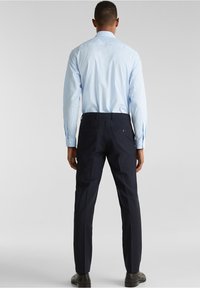 Ljusblå skjorta med långa ärmar, i kombination med mörknavy byxor. Byxorna har två bakfickor och en skräddarsydd passform.